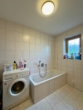 Badezimmer im Erdgeschoss mit Badewanne und Waschmaschinenanschluss