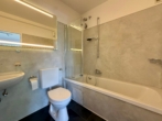 Modernisiertes Badezimmer mit Badewanne und Duschabtrennung