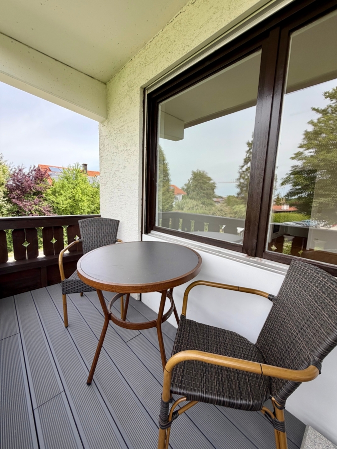 Überdachter Balkon mit hochwertiger Bestuhlung und Blick ins Grüne