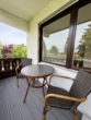Überdachter Balkon mit hochwertiger Bestuhlung und Blick ins Grüne